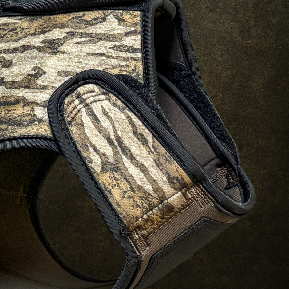 Camouflage-patterned ReKoile Outdoors Brand adjustable dog vest with black straps on a dark background