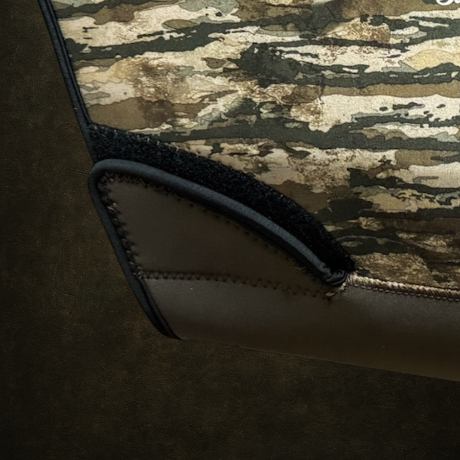 Close-up of a camouflage-patterned hunting dog vest showing the waist adjustment strap on a dark background