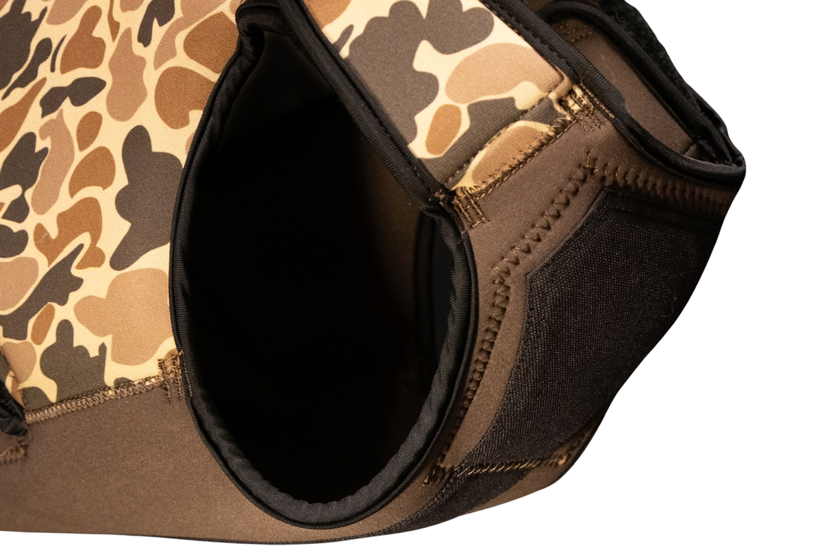 Close-up of a neoprene Dog Life Jacket, a brown and tan camouflage pattern on one side and solid brown on the other, with black trim.