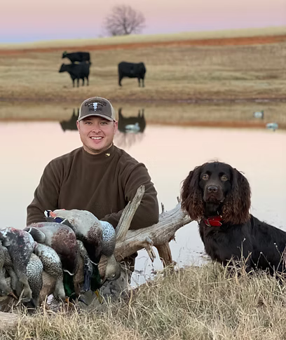 ReKoile Owner with his dog and hunting gear in a field with cows in the background