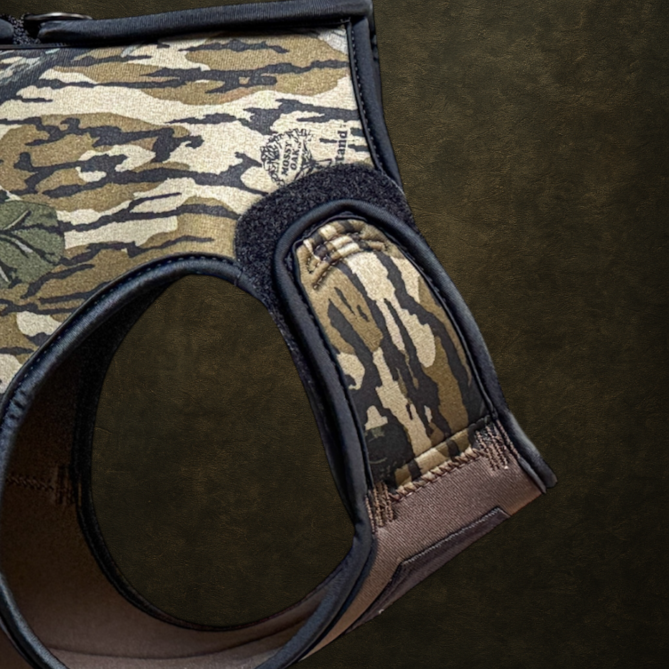 Camouflage-patterned dog harness showing the adjustable shoulder straps on a dark background. 