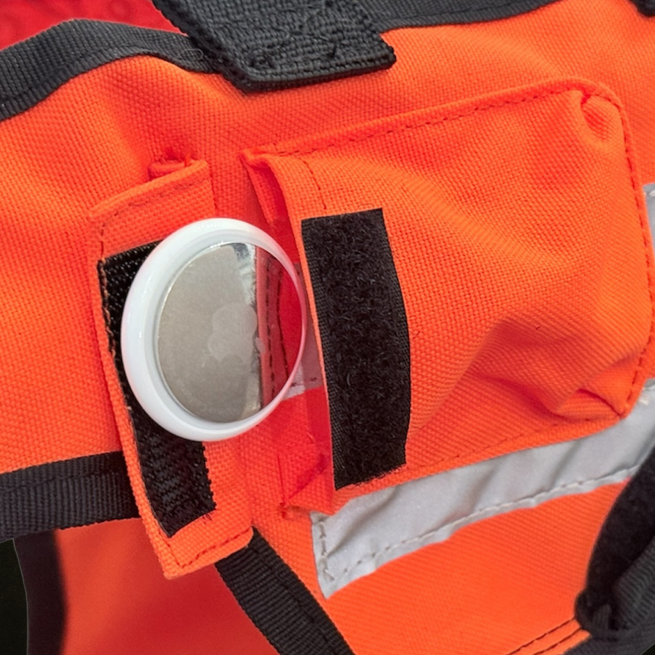 Close-up of an Pocket on an orange hunting dog vest with a white GPS Tracker.